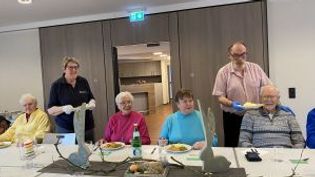 Helfer servieren den Gästen den Hauptgang an einen geschmückten Tisch