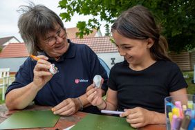 Eine Frau und ein Mädchen bemalen Steine