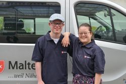 Auf dem Foto sind ein junger Mann und eine junge Frau zu sehen in Malteser T-Shirt, die in die Kamera lächeln.