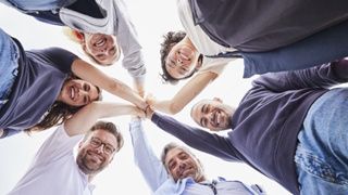 Eine Gruppe von Malteser Helferinnen und Helfern steht im Kreis. Sie sind im Zentrum mit den Händen verbunden