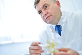 Ärztliche Fachkraft erläutert ein Wirbelsäulenmodell im Beratungsgespräch, helles Licht im Hintergrund.