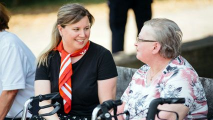 Eine Helferin der Malteser begleitet eine Dame bei einem Ausflug