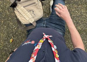 Teilansicht einer Person in Malteser Kleidung mit einem rotweißen Halstuch