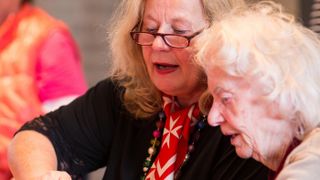 Eine Ehrenamtliche spricht mit einer älteren Dame