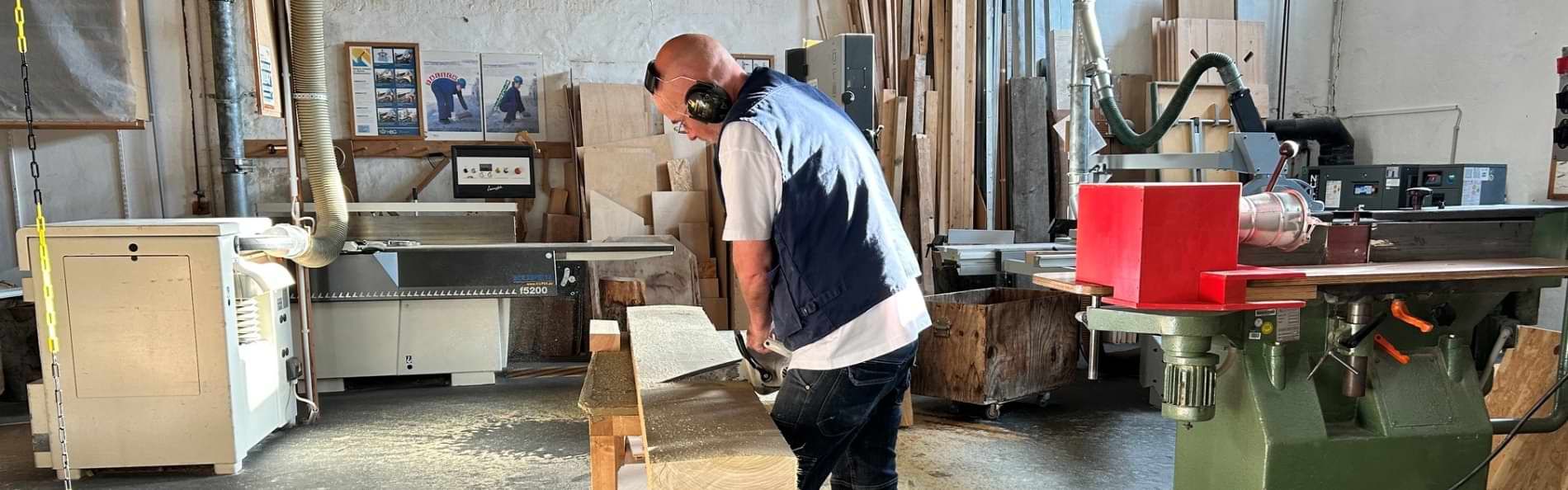 Ein Mann, der in einer Tischlerei an einem Holzbrett arbeitet.