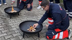 Ein Mann macht Feuer in einer Feuerschale