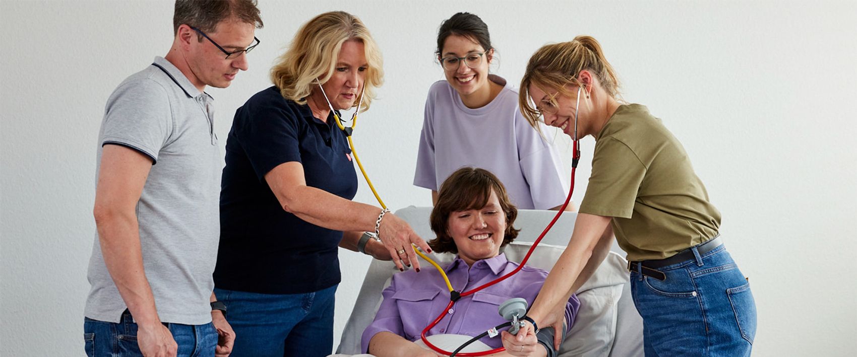 Bei der Ausbildung zu Pflegehilfskräften üben die Menschen am Bett mit einer Patientin. 