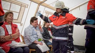 Ein Malteser in Einsatzkleidung kümmert sich um Menschen in einem Zelt 