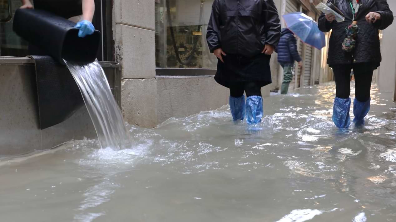 Menschen bei Hochwasser in einer kleinen Seitenstraße.
