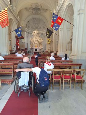 Ein Moment des Gebets: ein Mann im Rollstuhl und seine Begleiterin stehen im Gang vor dem Altar 