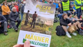Eine Hand hält ein Blatt mit Informationen zur Wallfahrt