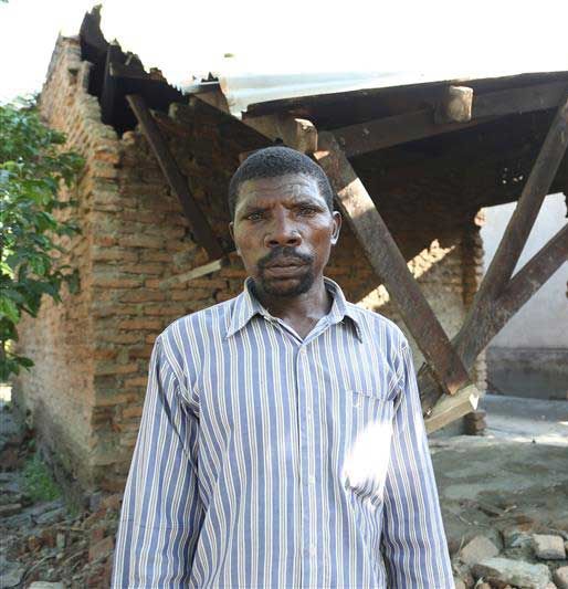 Ein Mann im Hemd vor einem zerstörten Haus