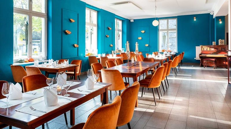 In einem stilvoll eingerichteten Restaurant mit blauen Wänden steht ein Klavier.