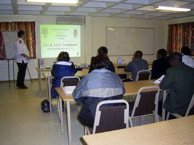 Participants attend a presentation on HIV treatment in a training room.