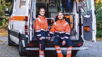 Eine junde Frau und ein junger mann stehen in Einsatzkleidung vor einem Einsatzwagen.