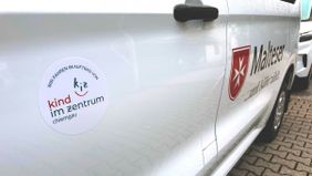 Teilansicht eines Kleinbusses mit Malteser Logo und Aufschrift "Wir fahren im Auftrag von KIZ Chiemgau"