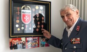 Malteser Ehrenamtlicher präsentiert stolz seine Auszeichnungen.