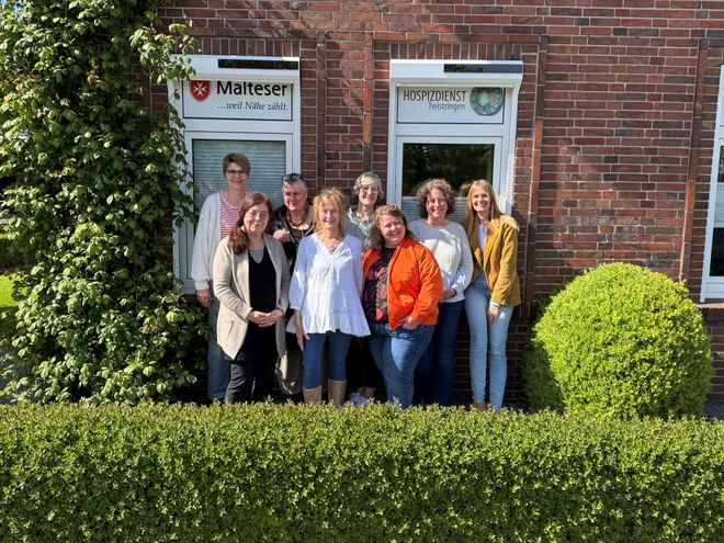 Die Kursteilnehmerinnen und -teilnehmer posieren für ein Gruppenfoto vor den Fenstern des Hospizdienstes der Malteser Twistringen