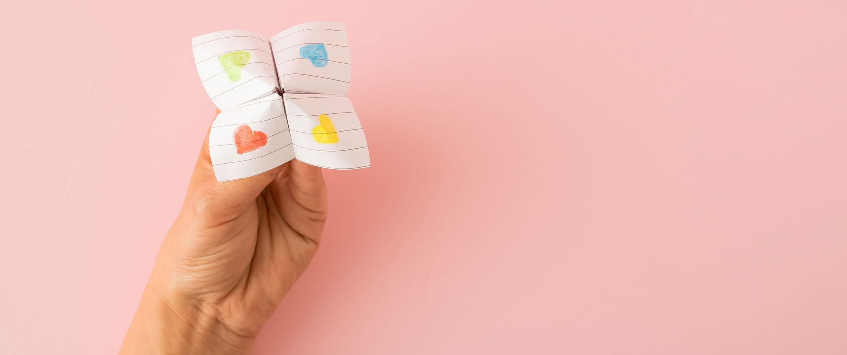 Eine Hand mit einem Himmel und Hölle-Spiel vor rosa Hintergrund
