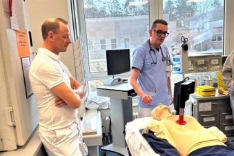 Zwei männliche Personen in einem Raum, vor ihnen ein Demo-Dummy