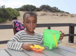Ein Kind des Kinderheims spielt bei einem Ausflug am Strand