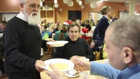 Ein Mann gibt einem Gast einen Teller mit warmem Essen. Foto: Hannemann/Malteser