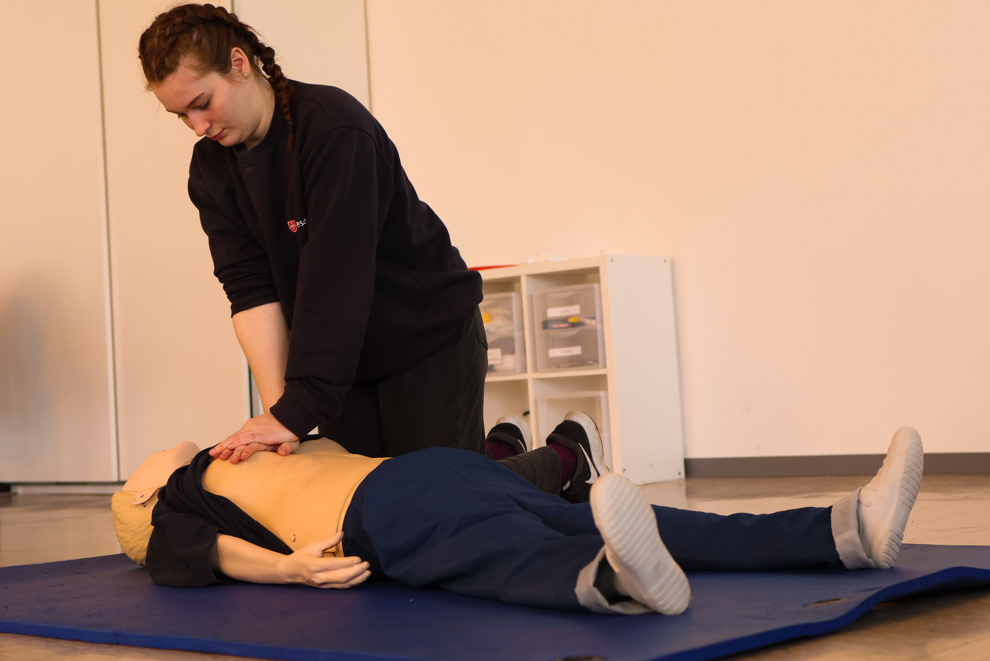 Erste-Hilfe-Ausbilderin demonstriert die Technik der Herzdruckmassage an einer Übungspuppe.