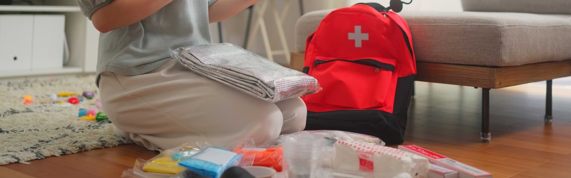 Eine lächelnde Frau packt und überprüft einen Notfall-Rucksack in ihrem Wohnzimmer.