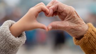 Eine junge und eine alte Hand zeigen gemeinsam ein Herz