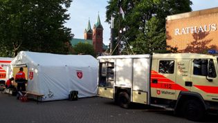 Zwei Sanitäter der Malteser mit einem Rucksack begleiten zwei Teilnehmerinnen einer Veranstaltung.