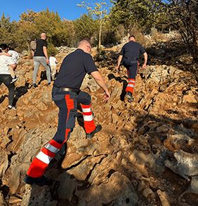 Zwei Einsatzkräfte der Malteser steigen den felsigen Erscheinungsberg hinauf.
