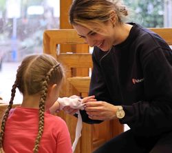 Eine junge Frau verbindet in einer Übung einem kleinen Mädchen die Hand