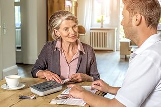 Ein Malteser Mitarbeiter erklärt einer Frau das Hausnotrufgerät.