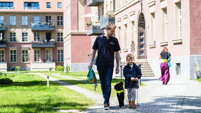 Ein junger Mann, ein Hund und ein kleiner Junge gehen auf einem gepflasterten Weg