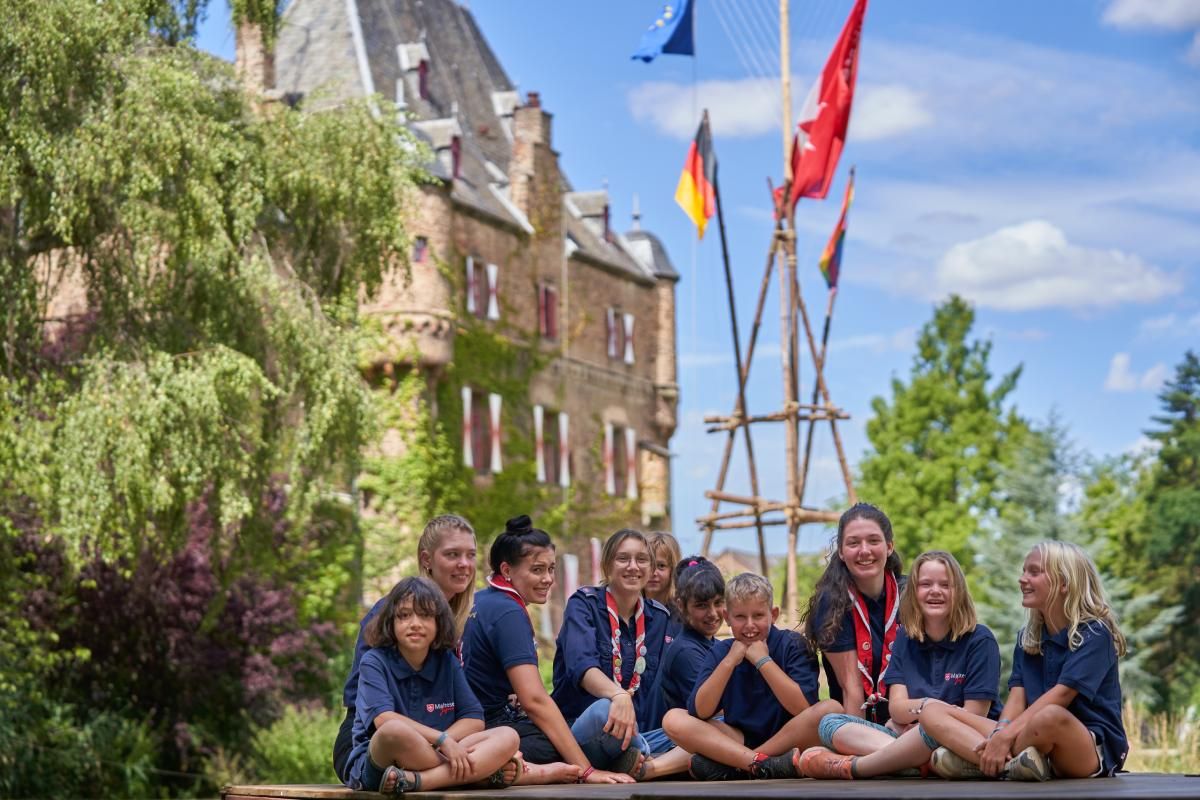 Eine Gruppe Kinder mit blauen T-Shirts vor einer Burg 