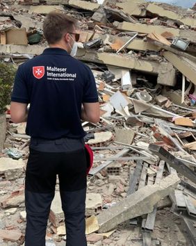 Ein Mann steht vor einem eingestürzten Haus. Foto: Malteser International