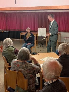 Jan Phillip Lehmker zeigt einer Freiwilligen der Malteser ein Buch, aus dem sie sich ein Wort merken sollte.