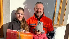Michael Soldanski, Leiter der Auslandshilfe, mit zwei Kindern und einem Hilfspaket