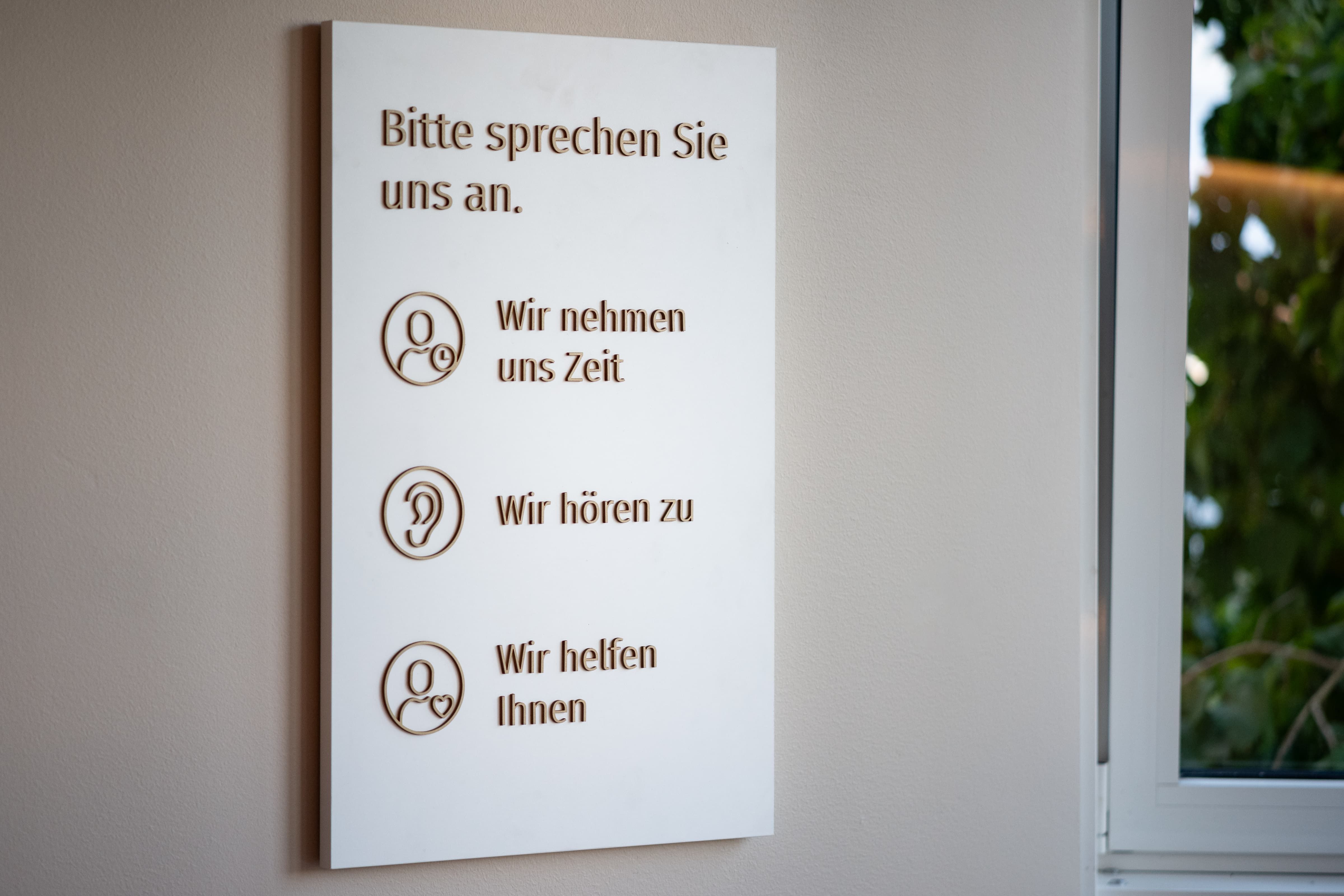 Infoboard mit Text und Symbolen "Wir nehmen uns Zeit", "Wir hören zu" und "Wir helfen Ihnen".