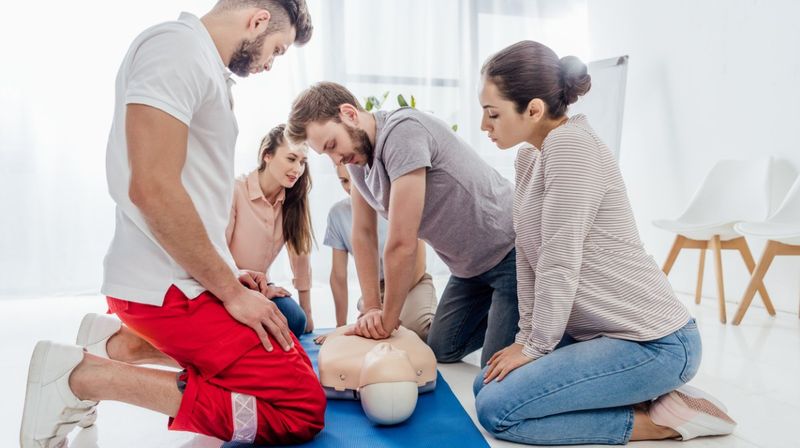 Gruppe von Menschen, die bei einem Erste-Hilfe-Kurs Wiederbelebungsmaßnahmen lernen
