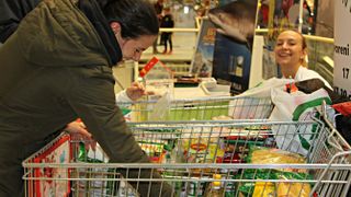 Eine Frau packt Lebensmittel in den Einkaufswagen