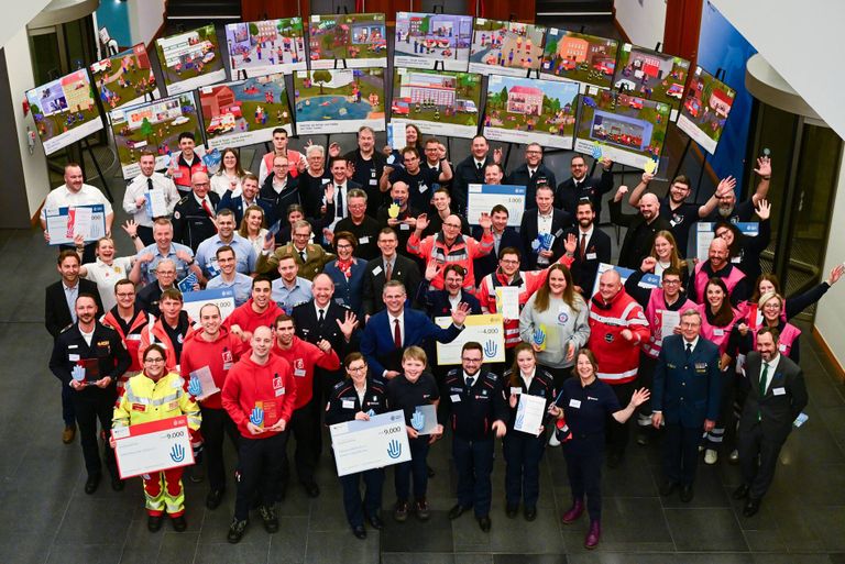 Viele Menschen mit freudigen Gesichtern winken in die Kamera.