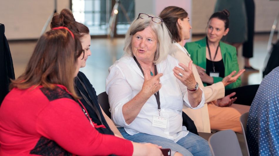 Menschen in einer Stuhlreihe reden miteinander