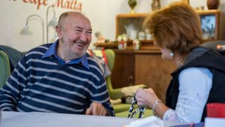 Ein älterer Mann unterhält sich lachend im Café Malta.