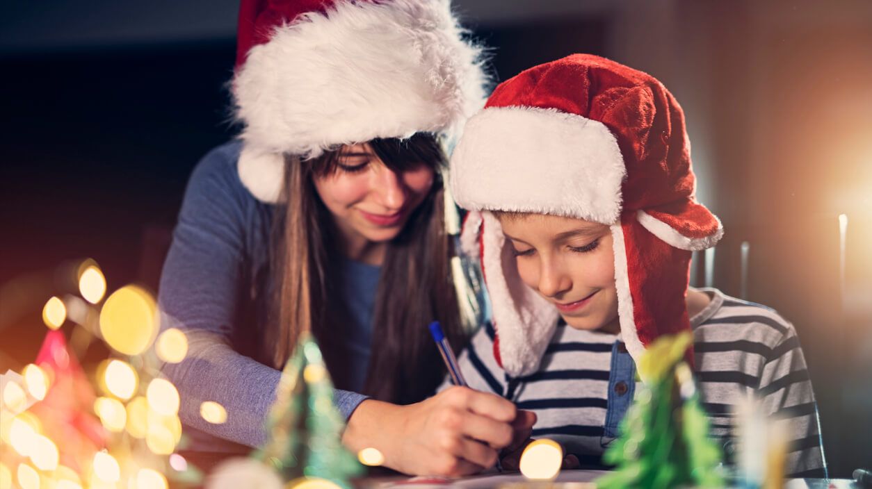 Junge Frau malt mit einem Kind Weihnachtsbilder