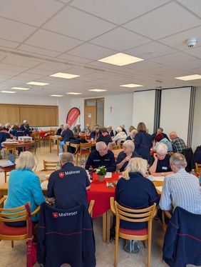 Die Ehrenamtlichen der Malteser sind in einem großen Tagungsraum in Gruppenarbeit vertieft