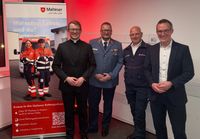 Lucas Weiss, Boris Falkenberg, Claus Kemp und Carsten Braun stehen vor einer Wand neben einem Banner auf dem Neujahrsempfang der Malteser